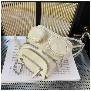 Detailopname van beige leren rugzak met glanzende afwerking en zilveren kettingdecoratie