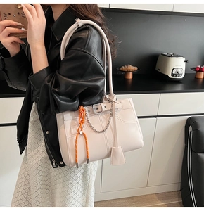 Detailed view of cream tote bag with quilted texture, silver chain, and orange rope strap