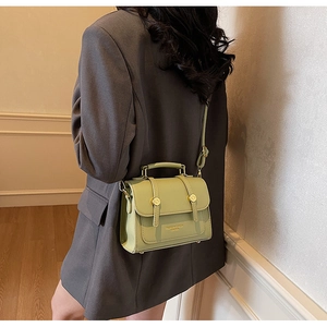 Close-up of avocado green leather handbag showing gold buckle and textured finish