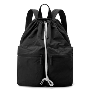 Detail of black nylon drawstring backpack featuring large front pockets and white cord