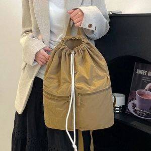 Detail of khaki nylon backpack with double zippers and white drawstring on female model