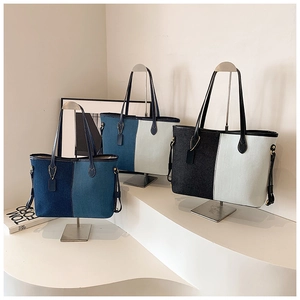 Détail de sacs cabas en denim bicolore avec panneaux contrastés et anses noires