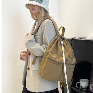 Detail of khaki nylon drawstring backpack showing the side view on a model