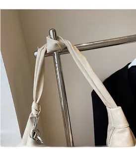 Detail of creamy white crossbody bag showing unique knotted handle and silver metal rings