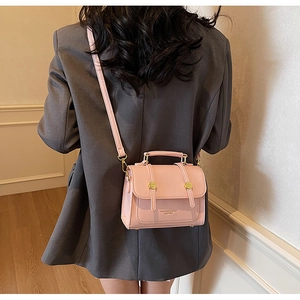 Detail of pink vintage crossbody bag featuring gold hardware and logo printed on matte leather