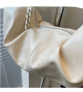 Detail of soft cream dumpling bag featuring premium leather texture and woven rope strap
