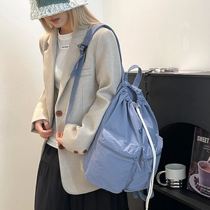 Detail of霧blue nylon drawstring backpack with double front zipper pockets on model