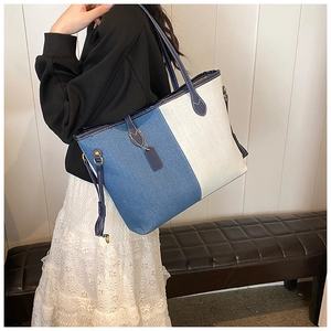 Détail du sac cabas bicolore en denim bleu et toile beige avec des finitions en métal doré