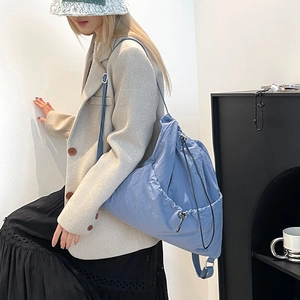 Detail of blue nylon drawstring backpack showing adjustable straps and textured fabric