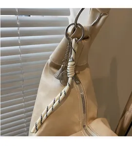 Detail of woven rope charm with tennis racket pendant on off-white leather bag