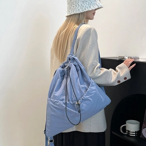Close-up of light blue drawstring backpack showing nylon texture and front pockets