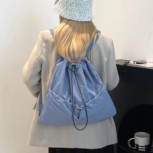 Detail view of light blue nylon drawstring backpack with front pocket and matte texture