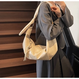 Close-up of beige croissant shoulder bag with soft leather texture and woven strap detail
