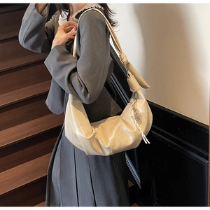 Detail of hobo shoulder bag with knotted wide strap and decorative metal tag