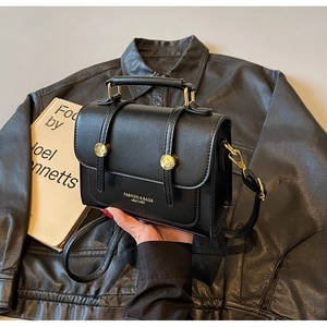 Detail of vintage black leather crossbody bag with gold buckles and chic top handle