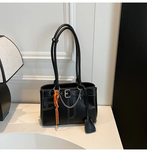 Detail of black leather tote bag featuring white contrast stitching and silver metal chain
