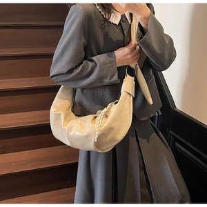 Detail of off-white pleated crescent bag with knot strap and textured leather finish