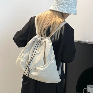 Detailed view of the large capacity cream-colored drawstring backpack on a model