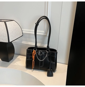 Detail of black leather tote bag with white contrast stitching and orange cord accents