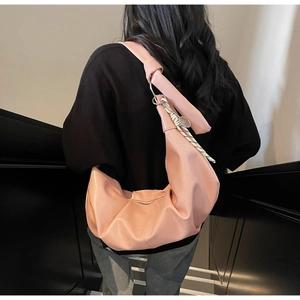 Close-up of pink crescent hobo bag with knotted strap and braided rope charm