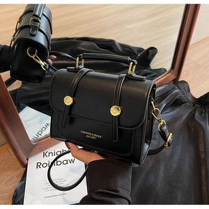 Close-up of black retro leather handbag with gold metal buckles and stylish branding