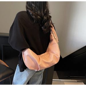 Pink crescent shoulder bag with silk scarf detail on a model in a modern indoor setting