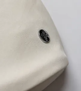 Detail of lightweight fabric texture and silver logo metal buckle on a crossbody bag