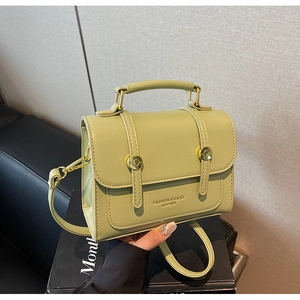 Detail of light green mini messenger bag with gold hardware and reinforced handle