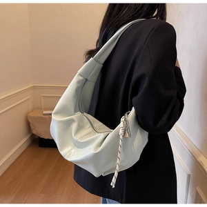 Detail shot of light mint green pleated half-moon shoulder bag with woven tassel accent