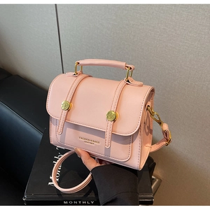 Detailed shot of pink leather crossbody bag with gold hardware and top handle strap