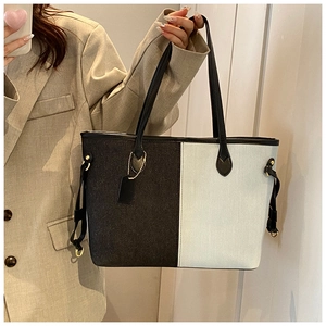 Détail du sac cabas bicolore avec texture denim, poignées en cuir et garnitures métalliques dorées