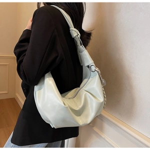 Detail of mint green pleated dumpling bag featuring a knotted wide shoulder strap