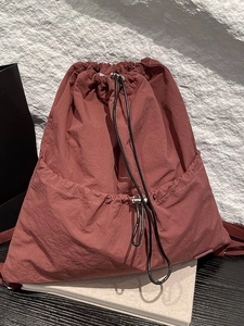 Rust red nylon drawstring backpack with lightweight fabric and adjustable black cords