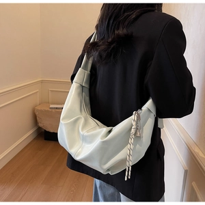 Detail of light mint green hobo bag with knotted strap and woven pendant decoration