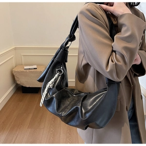 Macro detail of black hobo bag featuring pleated synthetic leather and knotted strap