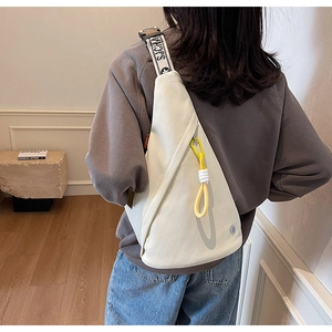 Detail of triangular cream sling bag with wide jacquard strap and utility ring