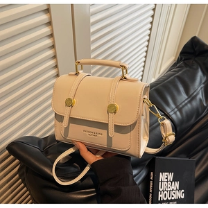 Detail of off-white messenger bag with gold buckles and adjustable shoulder strap