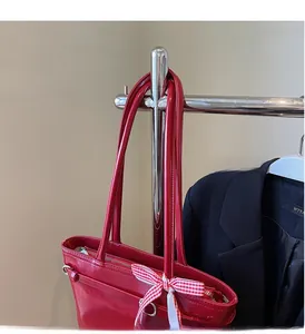 Détail du sac cabas en cuir rouge avec un ruban à carreaux et fermeture éclair