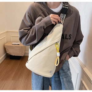 Detail of off-white crossbody chest bag featuring a branded strap and yellow zip charm