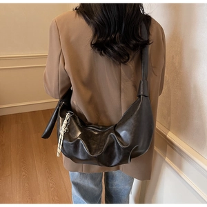 Model wearing a black pleated hobo bag with a striped scarf detail on shoulder