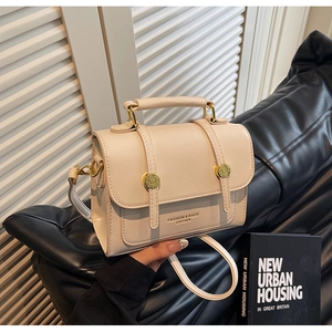 Detail of cream leather crossbody bag with top handle and gold hardware accents
