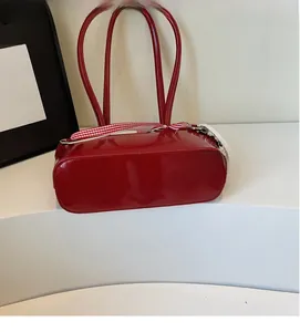 Détail d'un sac à bandoulière en cuir verni rouge avec ruban à carreaux et anses fines