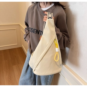 Detail of cream crossbody sling bag with bold yellow zippers and branded wide strap