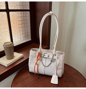 Dettaglio della borsa tote in pelle bianca con catena d'argento e ciondolo arancione