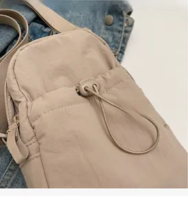 Detail of khaki nylon crossbody bag showing drawstring pocket and wrinkled fabric texture