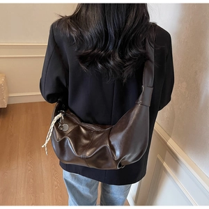Detail of dark brown hobo shoulder bag with contrast braided rope and metal charms