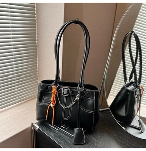 Detail of black leather tote bag with white stitching and bright orange rope accents