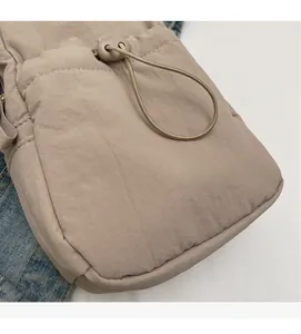 Detail of beige nylon crossbody bag showing soft wrinkled fabric and drawstring toggle