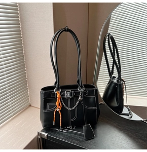 Detail of black leather tote bag with white contrast stitching and orange cord charm