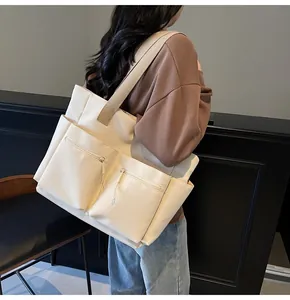 Detail of cream canvas tote bag with large double front zipper pockets and wide shoulder straps